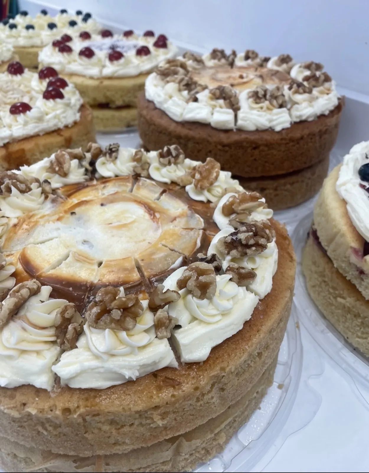Coffee and walnut style cake with cream swirls among other round cakes
