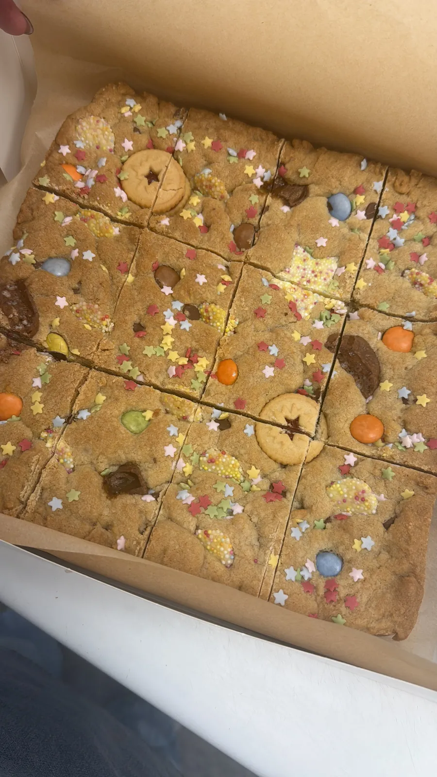Cookie traybake squares topped with sweets, sprinkles and biscuits
